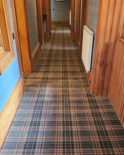 Tartan carpet runner fitted along a long hallway