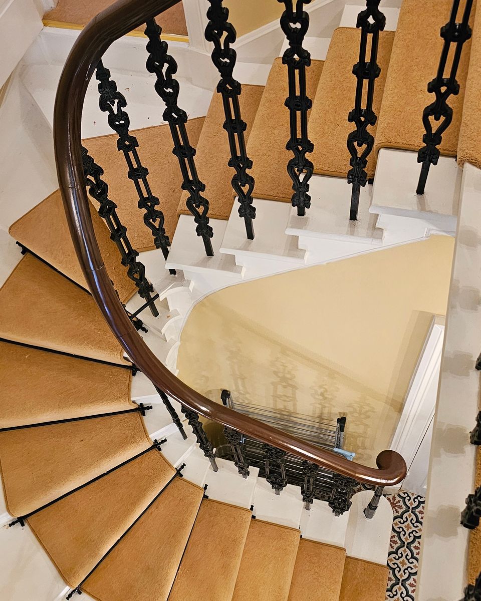 Gold runner fitted on a curved staircase with an iron balustrade