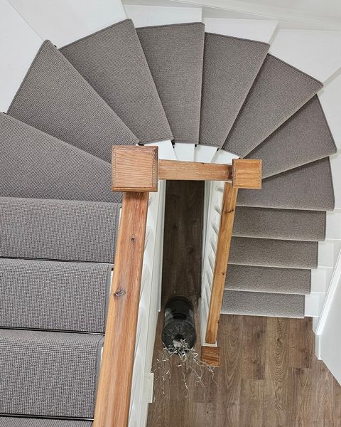 Grey carpet on a winding staircase, seen from the landing